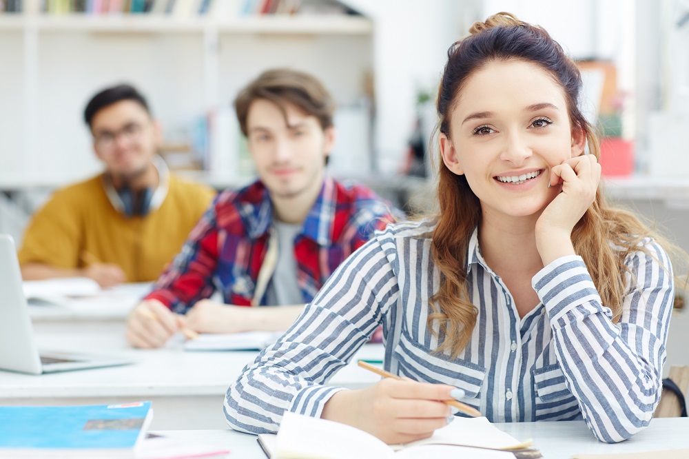 Happy young girl listening to teacher at lesson